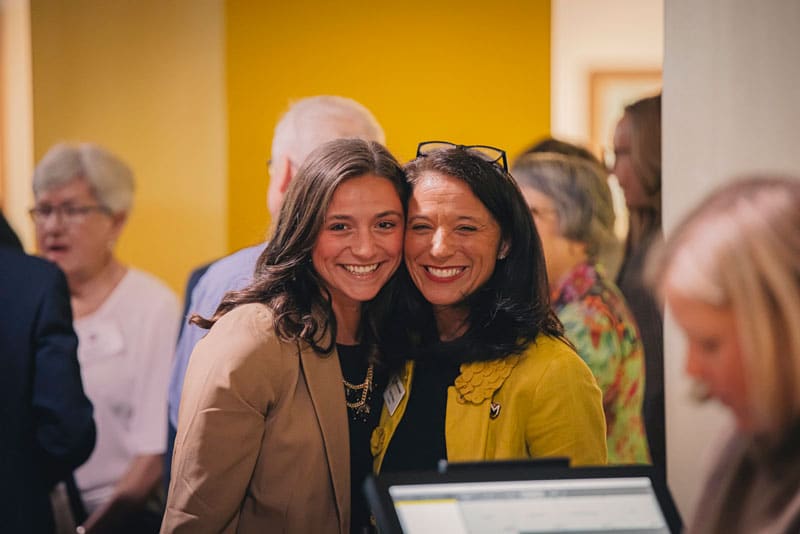 President Stacy Young poses with her daughter at a student research symposium.
