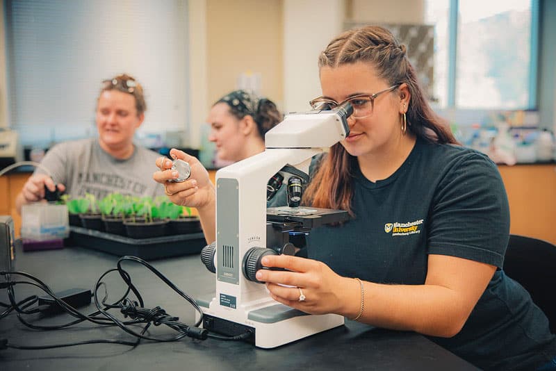 A female student looks through a microscope at a Manchester University Lab
