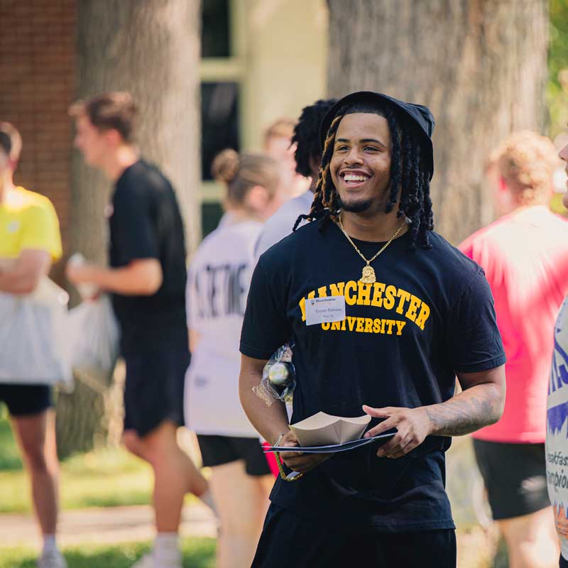 On Black & Gold Day, a student wearing an MU t-shirt and fedora smiles into the distance.