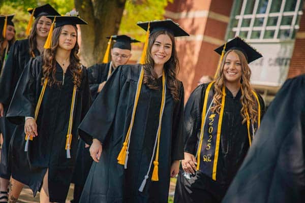 A female student and her friend pose together while waiting to enter the auditorium for commencement.