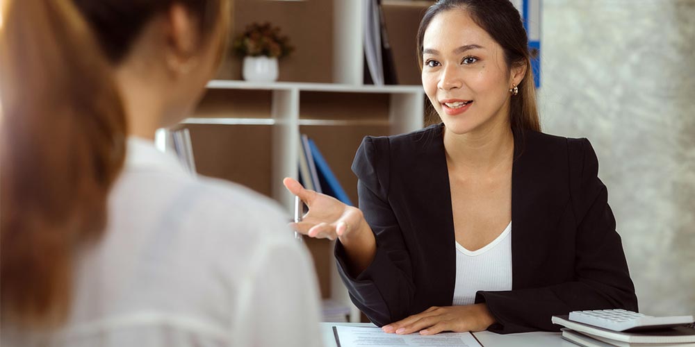 A female instructor leads a discussion across the desk.