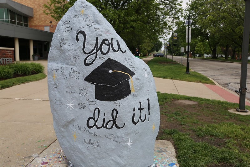 A rock on MU campus reads "you did it" with a grad cap. The students paint the rock every week to display a new message.