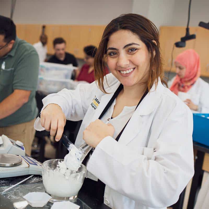 A female student uses a mixing bowl in the pharmacy lab at Manchester University Fort Wayne