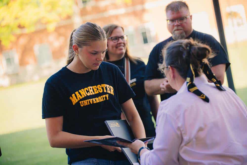 Black-and-Gold-MU-Shirt Female student reviews courses during a school visit.