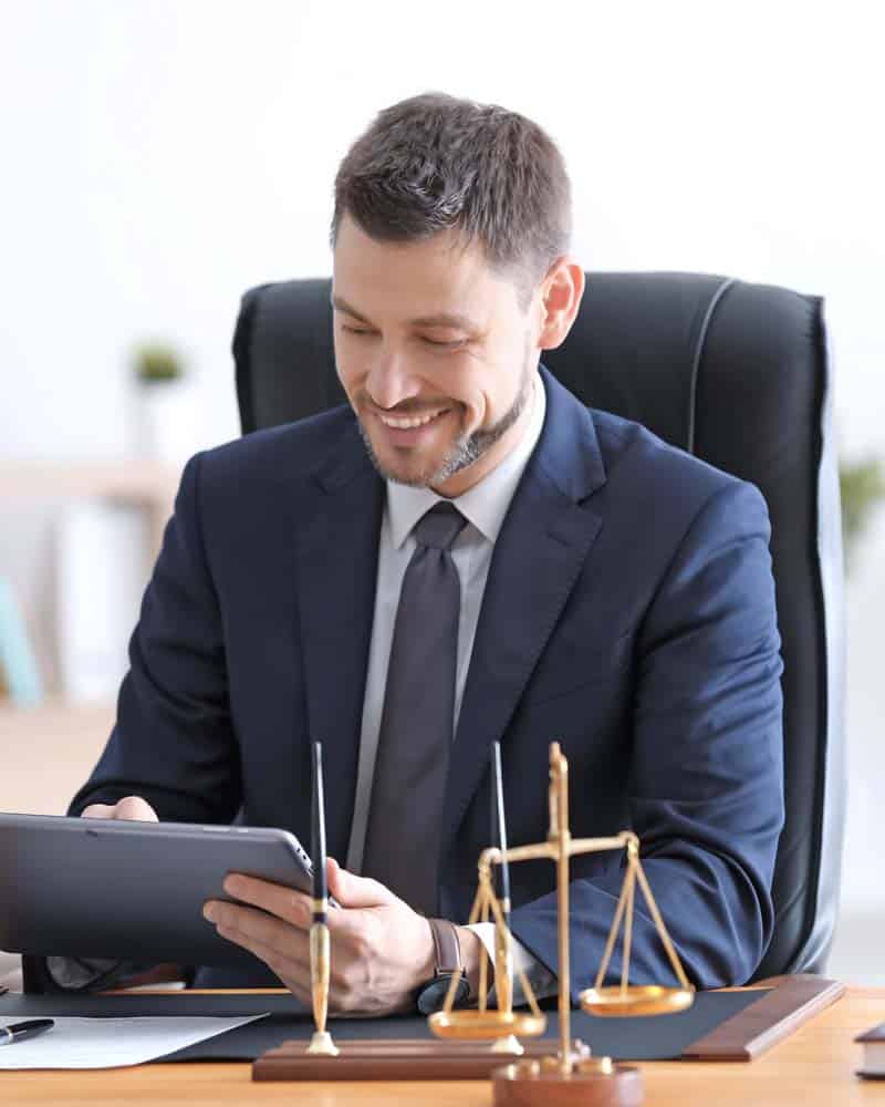 LawyerPrePro Lawyer reviews material on his iPad in front of a scale.