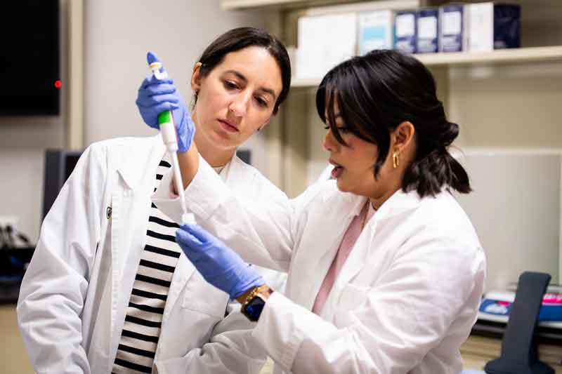 Instructor Ann Savariar-Drummond demonstrates piping material into a container for a student.