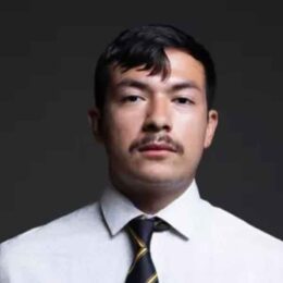 Portrait of Jonathan Sanchez - with mustache on black background in a tie.