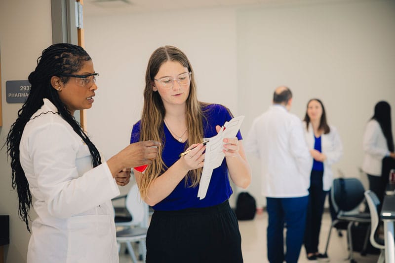 student and professor work together in the MU Pharmacy lab reviewing results on a printout