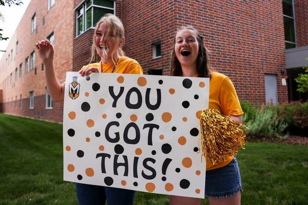 Two women Spartan students hold a sign that reads "You Got This!"