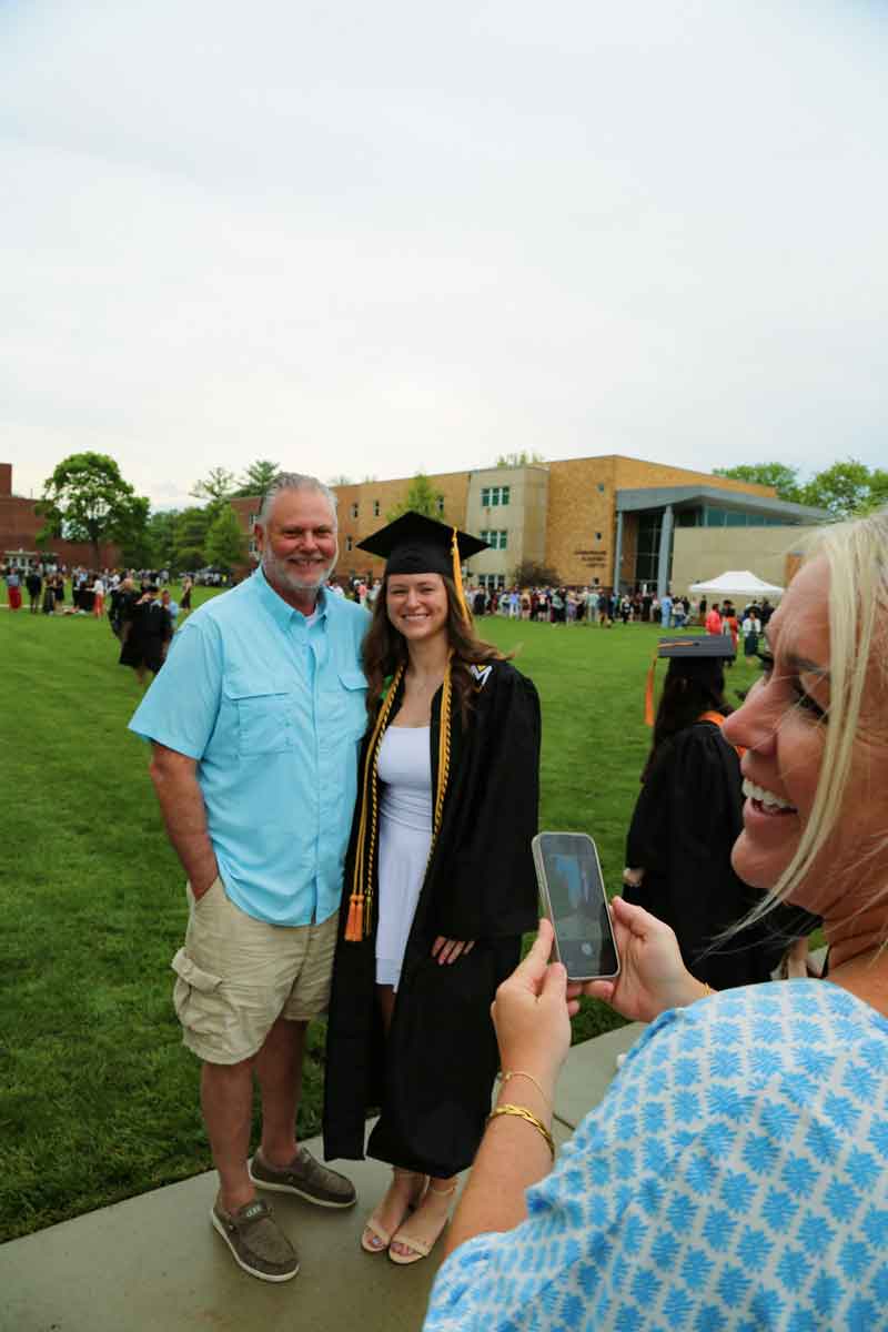 WayToGoParentsGradWR The mom takes a photo of her daughter with her dad at MU on commencement day.
